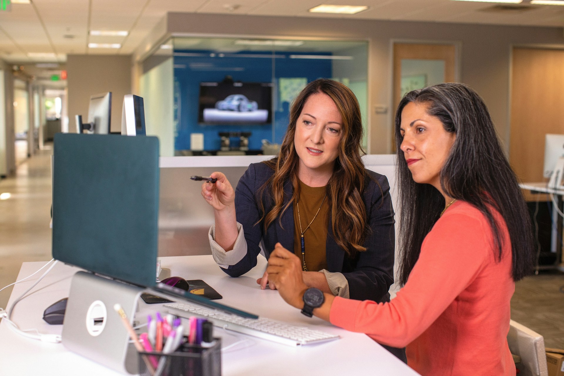 Two real estate agents collaborating at a computer, demonstrating teamwork and support.